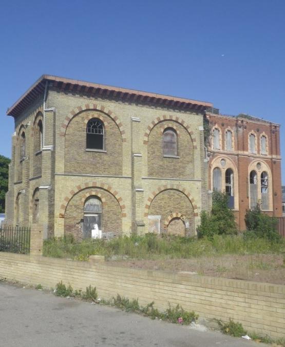 Property for sale by Auction An old, abandoned brick building with arched windows, partially deteriorated, and overgrown vines covering some sections. Standing on an unkempt lot with scattered wild plants under a clear blue sky, it evokes memories of Sheerness before the Water Tower development transformed the area. Presented by Palace Auctions