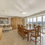 Property for sale by Auction A spacious, modern dining room at Tindale Towers on Dilks Street features a large wooden table with eight matching chairs. Floor-to-ceiling windows offer a scenic view. To the left is a curved kitchen countertop with a sink, while a beige couch and ornate wooden cabinet adorn the back wall of this Bishop DL14 9AP gem. Presented by Palace Auctions