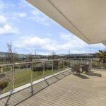 Property for sale by Auction A spacious balcony with glass railings and outdoor seating at Tindale Towers on Dilks Street overlooks a lush green landscape with trees and distant hills under a partly cloudy sky. The balcony, located in the Bishop DL14 9AP area, is connected to a building with large glass doors. Presented by Palace Auctions