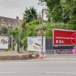 Property for sale by Auction A roadside scene features three billboards. The left billboard advertises Kent as the garden of England. The center billboard promotes a TV series. The right billboard highlights a plot of land with hope value for planning consent sold, boasting the slogan "Voted Best for Broadband and Mobile. Presented by Palace Auctions