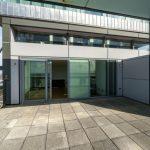 Property for sale by Auction A spacious balcony with a cement floor offers views of the city. Glass doors and windows lead to the interior of a modern Liverpool penthouse investment apartment. Metal and glass structures surround the area, providing a sleek and contemporary feel. The sky is clear in the background. Presented by Palace Auctions