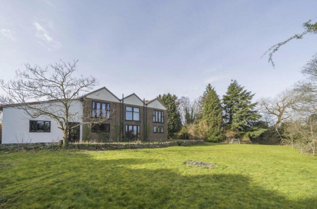 Property for sale by Auction A two-story house with a mix of brick and white stucco exterior stands on a large, well-maintained grassy lawn on Rowan Avenue. The house features large windows and is surrounded by trees and bushes under a clear sky. Presented by Palace Auctions