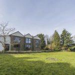 Property for sale by Auction A two-story house with a mix of brick and white stucco exterior stands on a large, well-maintained grassy lawn on Rowan Avenue. The house features large windows and is surrounded by trees and bushes under a clear sky. Presented by Palace Auctions