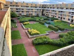 Property for sale by Auction The large apartment complex at 159 Collingwood Court, Washington, surrounds a green courtyard. Pathways intersect the grassy areas, which are lined with benches and bushes. A blue metal framework structure stands in the center. The complex has multiple floors with windows and balconies. Presented by Palace Auctions