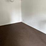 Property for sale by Auction An empty, unadorned room with plain white walls, a white ceiling, and a brown carpet. A single, round white light fixture hangs from the ceiling. The room has no furniture or decorations and is part of 13 Maynard Court on Rosefield Road in Staines-upon-Thames. Presented by Palace Auctions