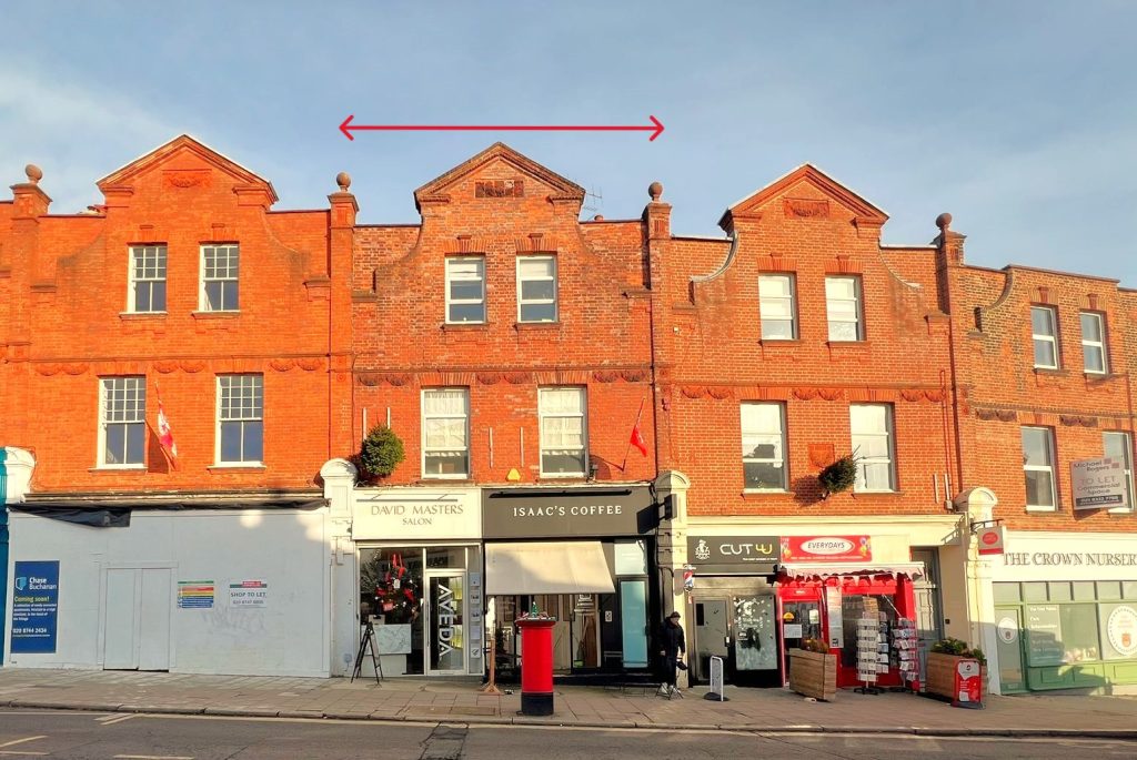 A row of red-brick buildings at 120 St. Margaret's Road, TW1 2AA, featuring store signs like "David Masters Salon," "Isaac's Coffee," "Cut-U," and "The Crown Nutrition." Available for sale by auction with Palace Auctions, London, this mixed commercial and residential investment boasts decorative brickwork and dormer windows. A few people are seen walking