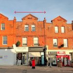 A row of red-brick buildings at 120 St. Margaret's Road, TW1 2AA, featuring store signs like "David Masters Salon," "Isaac's Coffee," "Cut-U," and "The Crown Nutrition." Available for sale by auction with Palace Auctions, London, this mixed commercial and residential investment boasts decorative brickwork and dormer windows. A few people are seen walking