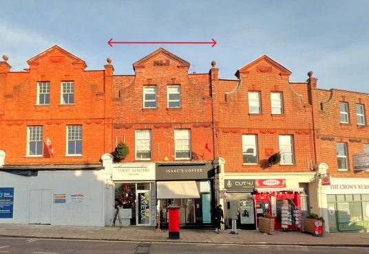 A row of red-brick buildings at 120 St. Margaret&#039;s Road, TW1 2AA, featuring store signs like &quot;David Masters Salon,&quot; &quot;Isaac&#039;s Coffee,&quot; &quot;Cut-U,&quot; and &quot;The Crown Nutrition.&quot; Available for sale by auction with Palace Auctions, London, this mixed commercial and residential investment boasts decorative brickwork and dormer windows. A few people are seen walking