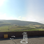 A scenic view of rolling green hills under a clear blue sky. In the foreground, part of a brick wall with a yellow waste bin can be seen. The road labeled "Channel Ave" runs along the bottom of the image. Land off Channel Avenue Porth Mid Glamorgan Wales (SOLD) by Palace Auctions - other plots may be available; contact the auctioneers.