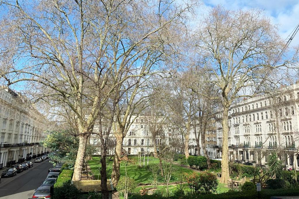 Peaceful urban park surrounded by classic European-style buildings, representing the location of a 3-star hotel for sale near Kensington Gardens