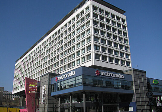 Modern multi-story building housing Metroradio under a clear blue sky