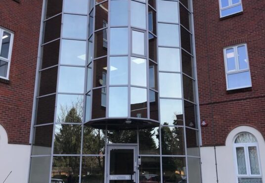 Modern glass-enclosed entrance attached to a traditional brick building on Edgeware Road for sale by auction