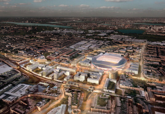 Aerial view of Tottenham an urban area with a large illuminated stadium at twilight illistrating property for sale.