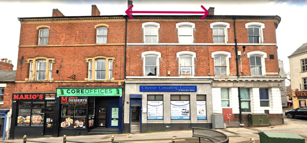 A street view of a two-story brick building with businesses on the ground level. One sign reads "MARIO's" next to "CORE OFFICES." Another sign for "Chester Consulting Limited" is visible, and a "To Let" sign is in one upper window. Pink arrows point to the roof.