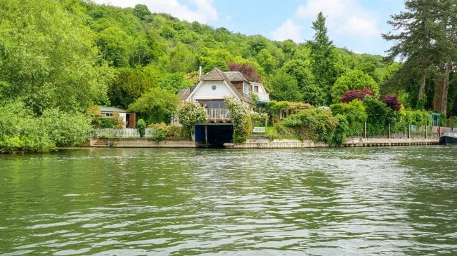 Charming two-story house by the water surrounded by lush greenery in Reading depicting the opportunity to build a similar property