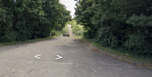 Paved road leading to a closed gate at Tanyard Farm, Hadlow, surrounded by lush greenery