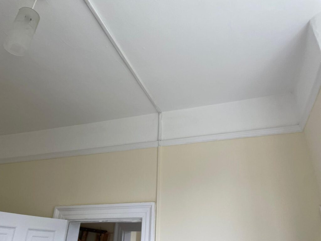 Property for sale by Auction A room with cream-colored walls and a white ceiling. The ceiling has a small light fixture, and there is a white door partially open, leading to another room. The door frame and wall have white trim along the edges. Presented by Palace Auctions