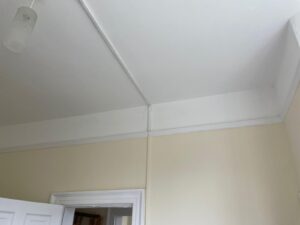 Property for sale by Auction A room with cream-colored walls and a white ceiling. The ceiling has a small light fixture, and there is a white door partially open, leading to another room. The door frame and wall have white trim along the edges. Presented by Palace Auctions