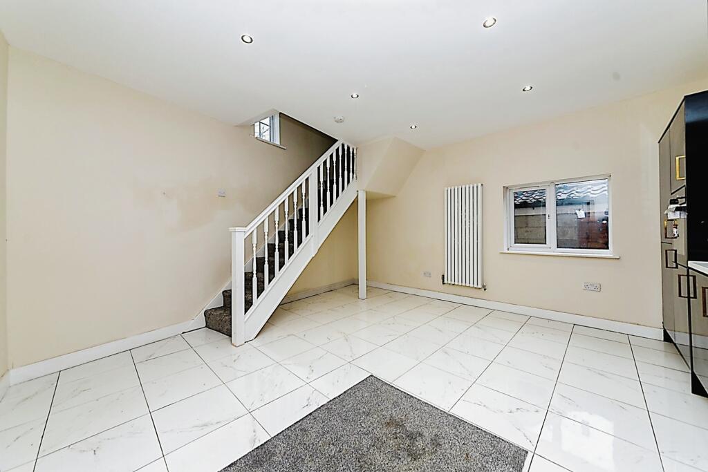 Property for sale by Auction A clean, modern room with white tiled floors and light-colored walls. A carpeted staircase with a white banister leads upwards. A single window is on the wall to the right, and a tall radiator stands beside it, creating a substantial residential and development opportunity. Recessed lighting fixtures are set in the ceiling.
 Presented by Palace Auctions