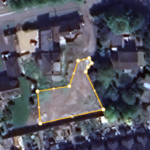 Property for sale by Auction Aerial view of a residential area with trees and houses. A plot of land in the center is outlined in yellow with connected points, highlighting its boundaries, presenting a substantial residential and development opportunity. The surrounding area includes roads, various buildings, and greenery. Presented by Palace Auctions