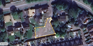 Property for sale by Auction Aerial view of a residential area with trees and houses. A plot of land in the center is outlined in yellow with connected points, highlighting its boundaries, presenting a substantial residential and development opportunity. The surrounding area includes roads, various buildings, and greenery. Presented by Palace Auctions