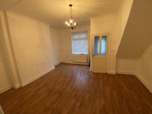 Property for sale by Auction A small, empty room with white walls and a wooden floor. The room has a single window with blinds, a hanging light fixture, and a glass-paneled door. The ceiling has decorative molding. Presented by Palace Auctions