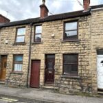 Property for sale by Auction A row of traditional terraced houses with stone facades and chimneys, featuring three front doors in different colors: brown, maroon, and white. The street is quiet, with a cloudy sky overhead. Presented by Palace Auctions
