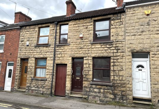 Property for sale by Auction A row of traditional terraced houses with stone facades and chimneys, featuring three front doors in different colors: brown, maroon, and white. The street is quiet, with a cloudy sky overhead. Presented by Palace Auctions