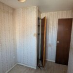 Property for sale by Auction A narrow, empty room with floral wallpaper and a light wooden floor. The room has two dark wooden doors, one slightly ajar revealing a small closet. A single ceiling light fixture is visible. Presented by Palace Auctions