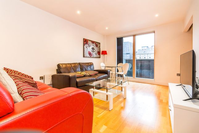 Property for sale by Auction Modern living room with red and black sofas, a glass coffee table, a flat-screen TV on a white stand, and a dining area with glass-top table and chairs. Large window offers cityscape view. Bright artwork decorates the wall. Presented by Palace Auctions