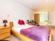 Property for sale by Auction A spacious bedroom with a wooden bed, purple bedspread, and red pillows. A wooden bedside table with a red lamp is beside the bed. A wooden wardrobe stands against the wall. There's a large window letting in natural light. Presented by Palace Auctions
