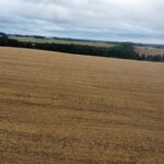 Property for sale A wide, harvested field under a cloudy sky stretches towards a line of distant trees and rolling hills—an ideal setting for speculative development land in Lane End, High Wycombe, with patches of greenery on the horizon. Presented by Palace Auctions