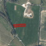 Property for sale Aerial view of green fields intersected by roads, with a freehold land parcel Surrey outlined in red near the center-left, adjacent to Lambfield Road. Buildings and trees are visible at the top and bottom edges. Presented by Palace Auctions