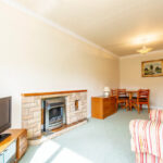 Property for sale A bright living room in this one bedroom flat Nottingham features a TV on a stand, stone fireplace, striped armchair, and a small dining area with wooden chairs and table. A painting hangs on the wall above the dining area. Presented by Palace Auctions