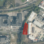 Property for sale Aerial view of an industrial area in Crawley bordered by roads, buildings, and green space. A triangular plot of land for sale Crawley is highlighted in red near Russell Way, surrounded by warehouses and office buildings. Presented by Palace Auctions