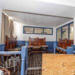 Property for sale Old-fashioned pub seating area with wooden booths, blue trim, plaid carpet, and a wooden partition in the foreground. This traditional public house conversion Newcastle area features brass wall lamps, curtained windows, and classic charm. Presented by Palace Auctions