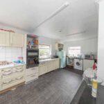 Property for sale A bright kitchen in a traditional public house conversion, featuring cream cabinets, a black oven, washing machine, and fridge. Countertops hold various items and groceries; a window lets in natural light over dark tiled floors. Located in the Newcastle area. Presented by Palace Auctions