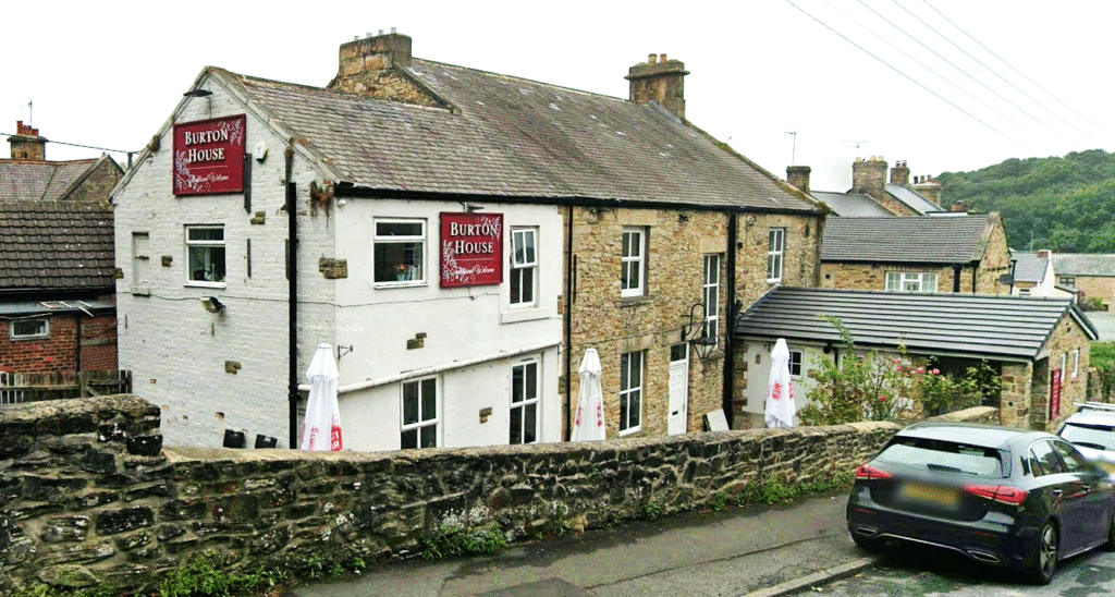 Property for sale A stone and white-painted building labeled "Brook House" stands behind a stone wall on a sloped street—a great example of a traditional public house conversion in the Newcastle area. Outdoor umbrellas and a parked car sit at its entrance. Presented by Palace Auctions