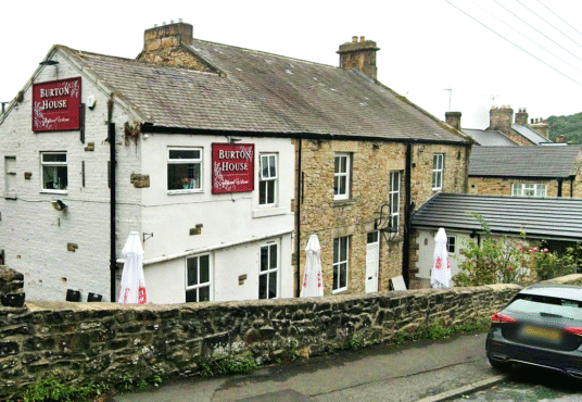 Property for sale A stone and white-painted building labeled "Brook House" stands behind a stone wall on a sloped street—a great example of a traditional public house conversion in the Newcastle area. Outdoor umbrellas and a parked car sit at its entrance. Presented by Palace Auctions