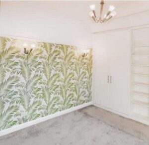 Property for sale A bright room in this Altrincham period flat features leafy green palm-patterned wallpaper, built-in white wardrobes with shelves, light gray carpet, and modern wall and ceiling lights. Presented by Palace Auctions