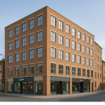 Property for sale A modern, four-story brick mixed-use investment in Wisbech stands on a quiet street corner, featuring large windows and ground-floor shops like "Savvy." Located at PE13 1AF, this property offers great one-bed apartment block potential. Presented by Palace Auctions
