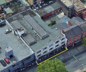 Property for sale Aerial view of a row of buildings along Cricklewood Broadway, with Crusader House, 283 Cricklewood Broadway, London NW2 6NX outlined in yellow. Rooftops, parked cars, and trees are visible nearby. Presented by Palace Auctions
