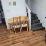 Property for sale A small wooden table with two chairs sits against a white wall near a carpeted staircase in this Abbey Lane Investment Property. Two framed pictures hang above the table, with wood flooring and a partially visible refrigerator on the right. Presented by Palace Auctions