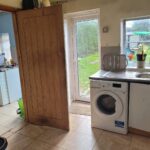 Property for sale A bright kitchen in one of the 2-bed houses Leicester offers, featuring a washing machine under the counter, stainless steel sink, dish rack, potted plants on the windowsill, and doors leading to a utility room and green garden. Presented by Palace Auctions