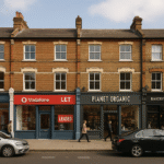 Property for sale A street view of Richmond TW9 commercial units shows brick buildings with shops like Vodafone, a "LET" unit, and Planet Organic. People walk the sidewalk, cars are parked, capturing the essence of a prime Richmond retail investment opportunity. Presented by Palace Auctions
