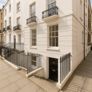 Property for sale by Auction A white Georgian-style townhouse with black railings, small balconies, and steps down to a black basement door marked "16." Presented by Palace Auctions London, the building sits on a clean, paved city street. Presented by Palace Auctions
