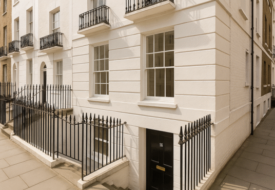 Property for sale by Auction A white Georgian-style townhouse with black railings, small balconies, and steps down to a black basement door marked "16." Presented by Palace Auctions London, the building sits on a clean, paved city street. Presented by Palace Auctions
