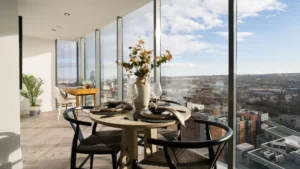 Property for sale Modern dining area with round table set for four, large vase with flowers, and floor-to-ceiling windows showcasing panoramic city views. Light wood floors and minimalistic décor enhance this bright space in Langford Tower Sheffield. Presented by Palace Auctions