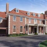Property for sale A large, two-story brick house with white trim, multiple chimneys, and a red tile roof—an exceptional Hampstead Garden Suburb luxury home surrounded by trees and blue sky—offers elegant living in the heart of London. Presented by Palace Auctions