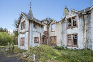 Property for sale An old, abandoned two-story house with broken windows, peeling white paint, and overgrown vegetation evokes the charm of a forgotten Scottish manor house development under a clear blue sky. Presented by Palace Auctions
